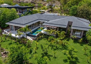 A modern house with a swimming pool, surrounded by lush greenery and palm trees. - New Listing • Villa Bosque del Coco • 4BR Luxury Villa • Coco Bay (Playas del Coco)