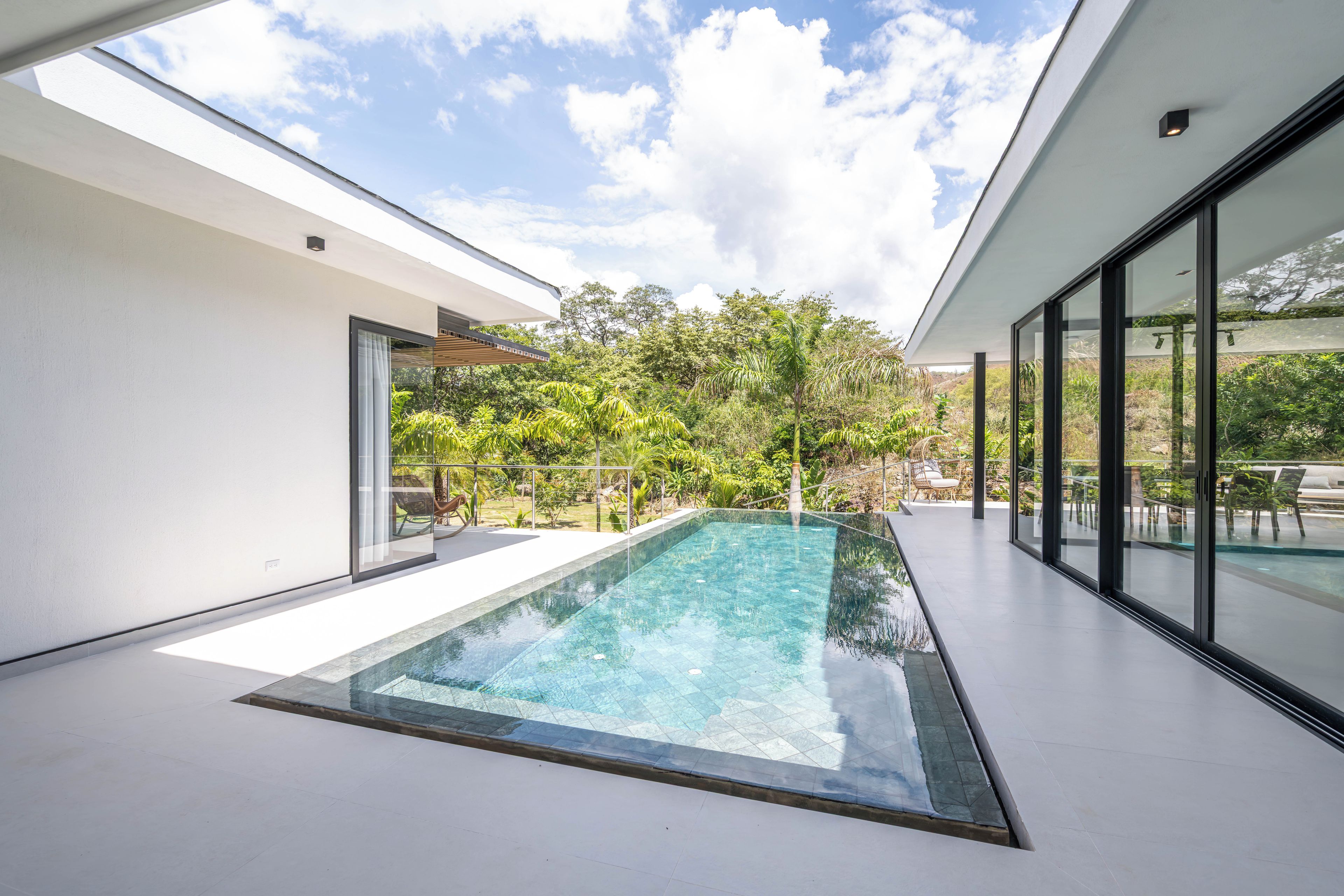 A modern outdoor pool area with a clear view of the sky and surrounding greenery.