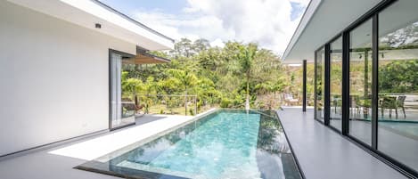 A modern outdoor pool area with a clear view of the sky and surrounding greenery.