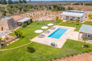 Ein Wohnhaus mit Pool, Sitzgelegenheiten im Freien und einem gepflegten Rasen.