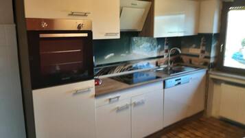 A compact kitchen with a built-in oven, a sink, and a window.