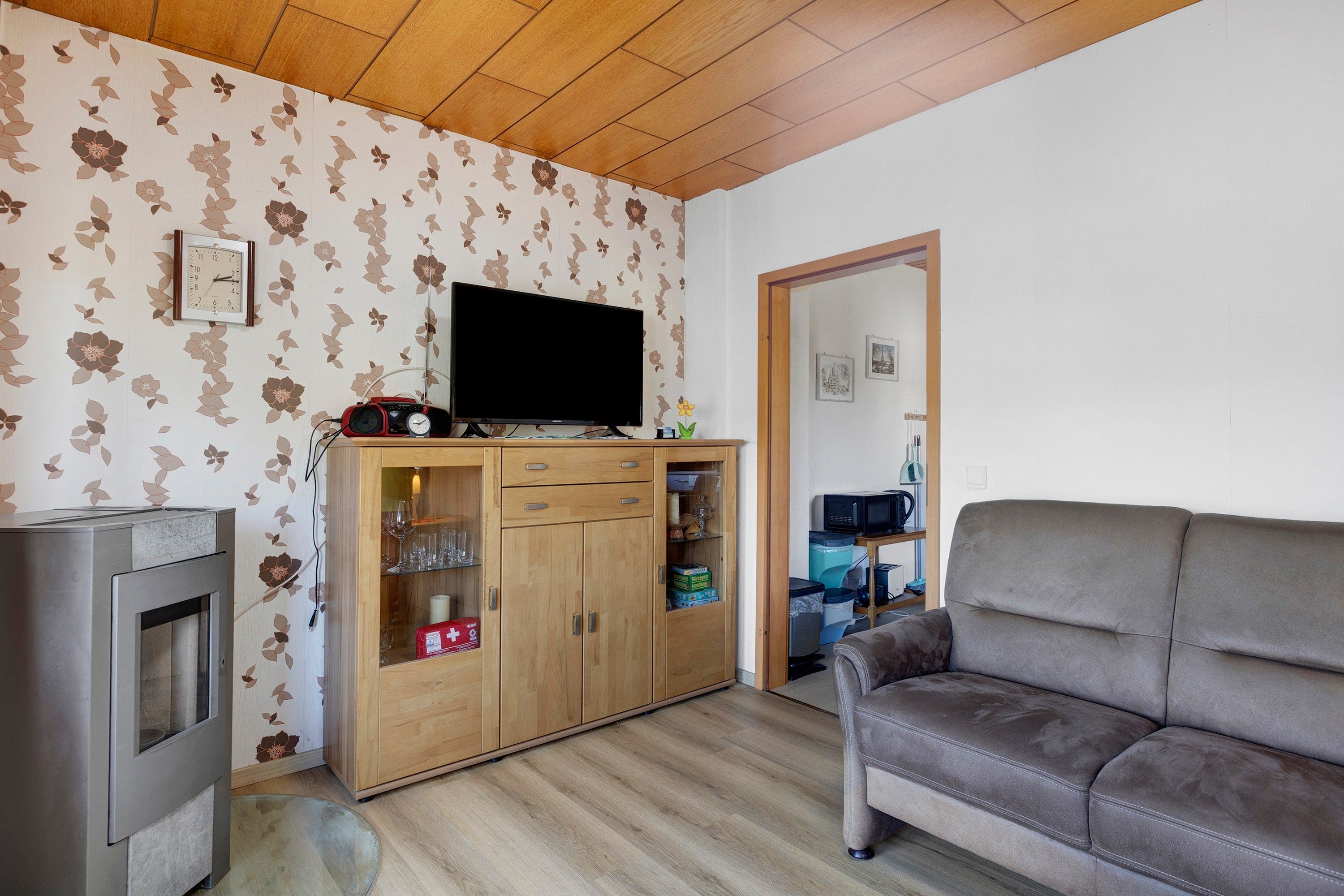 A living room with a flat-screen TV, wooden cabinet, sofa, and a fireplace.