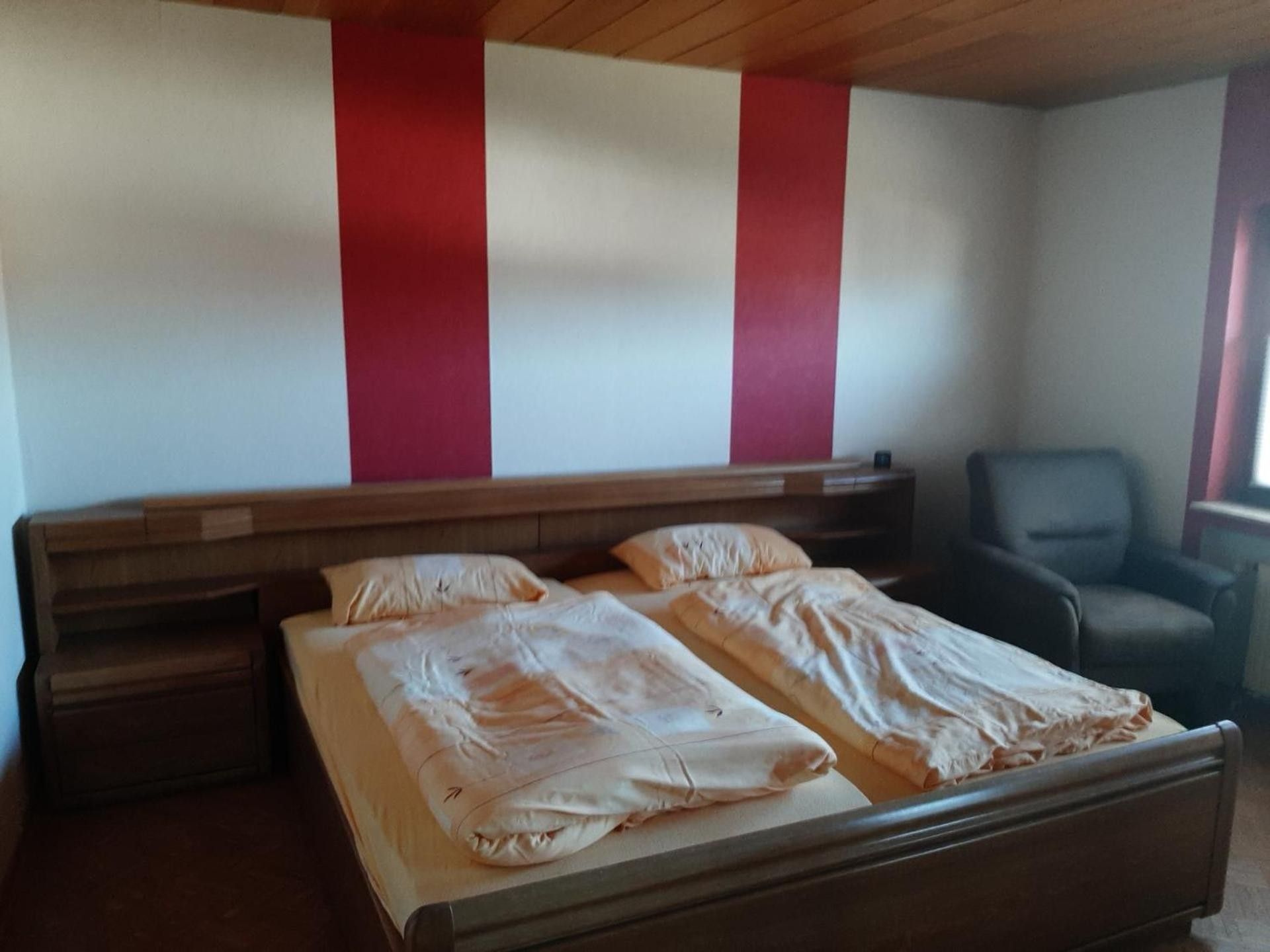 Ein Schlafzimmer mit einem Bett, einem Sessel und einem hölzernen Kopfteil.