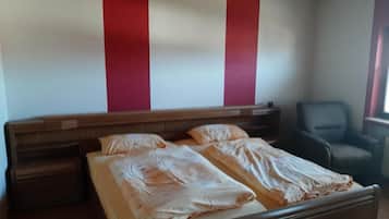 Ein Schlafzimmer mit einem Bett, einem Sessel und einem hölzernen Kopfteil.