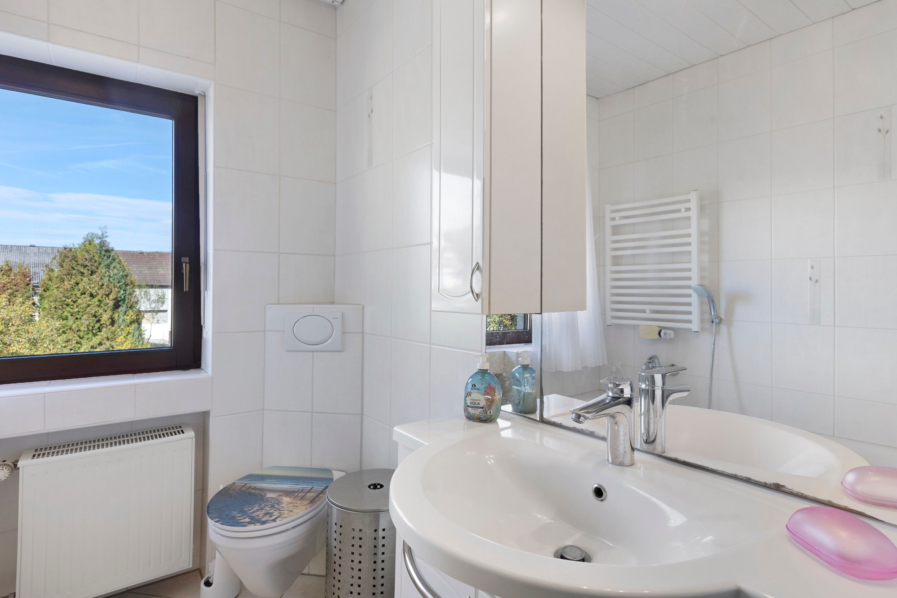 Ein modernes Badezimmer mit Toilette, Bidet, Waschbecken und einem Fenster.