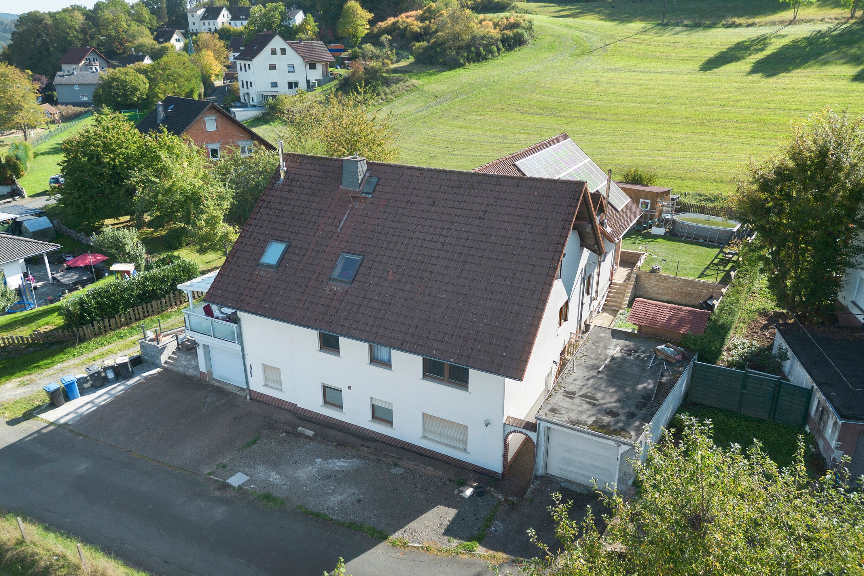 Ein zweigeschossiges Gebäude mit geneigtem Dach, einem eingezäunten Hof und freiem Blick auf die umliegende Landschaft.