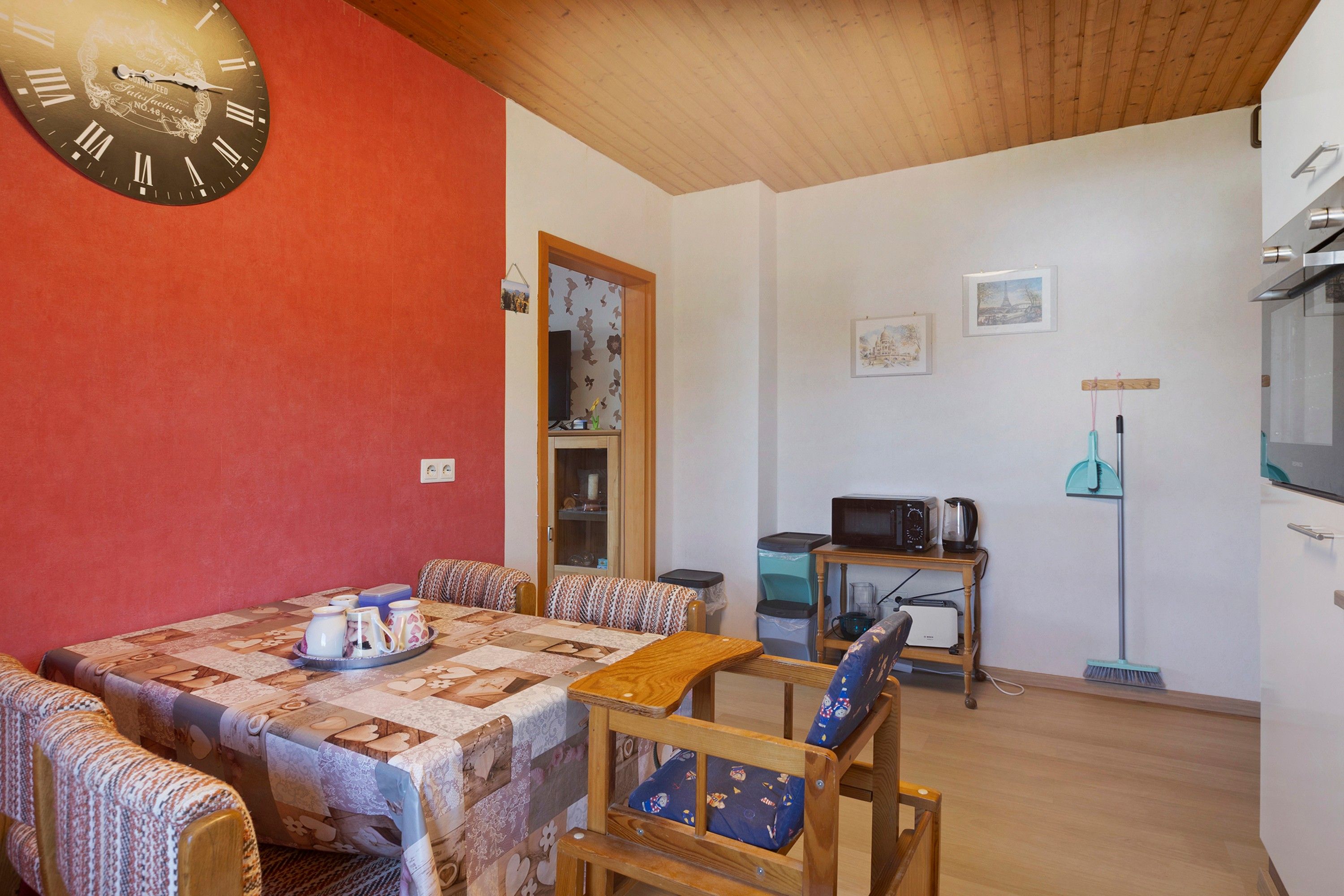Un comedor acogedor con una mesa de madera, mantel estampado y sillas con cojines.