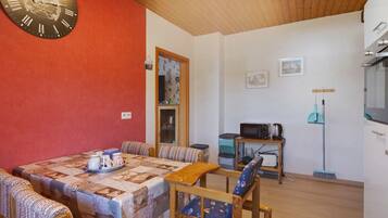 Un comedor acogedor con una mesa de madera, mantel estampado y sillas con cojines.
