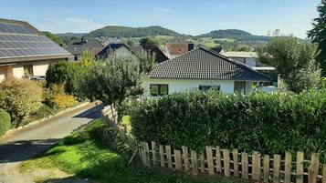 A residential area with houses, a road, and a hilly landscape in the background.