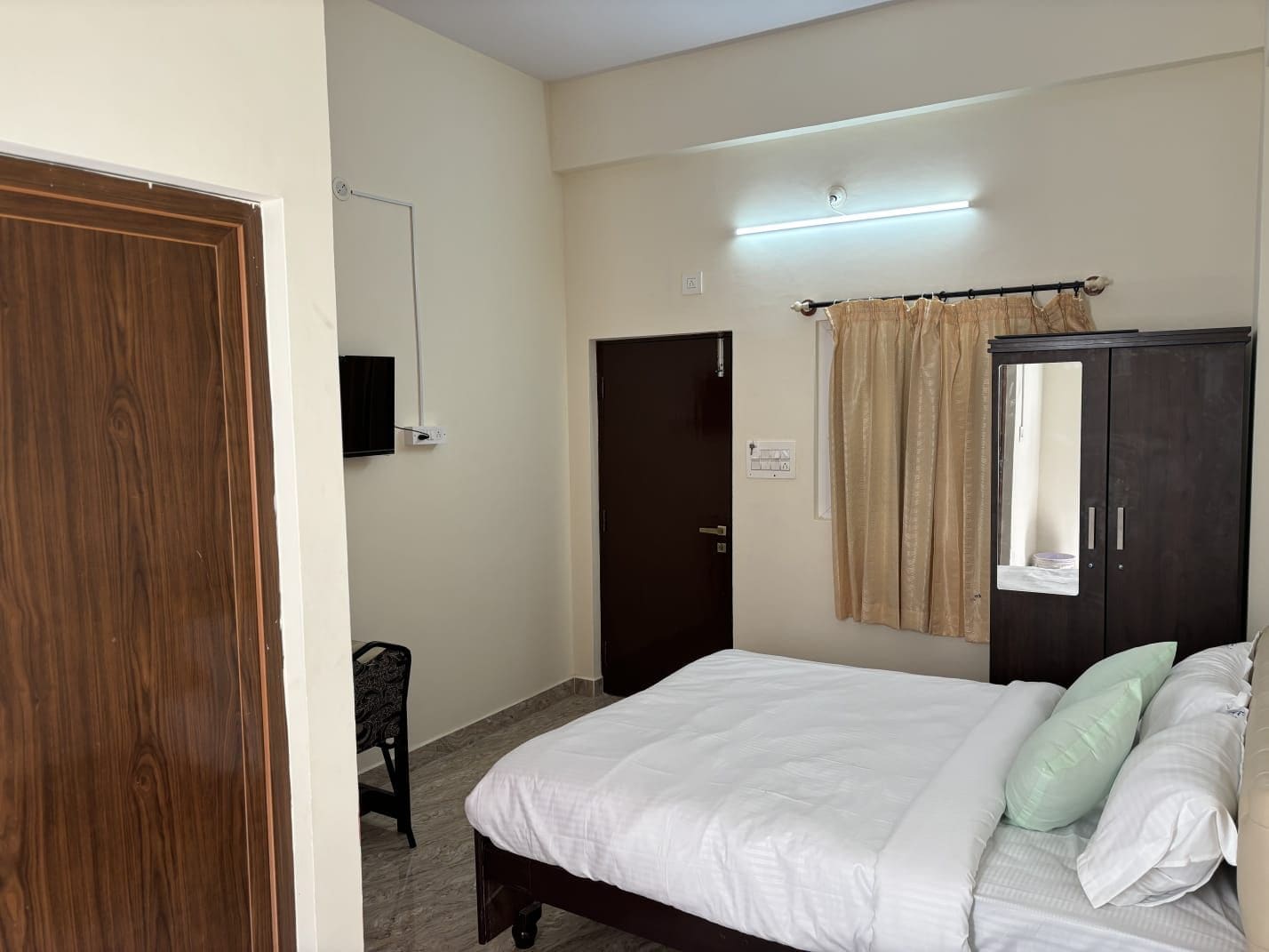 Un dormitorio con cama, armario, televisor y puerta.