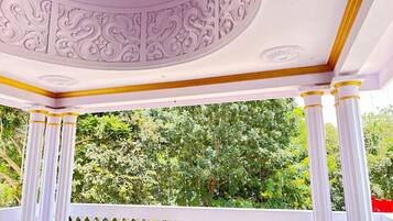 A gazebo with ornate ceiling and white columns with golden bases.