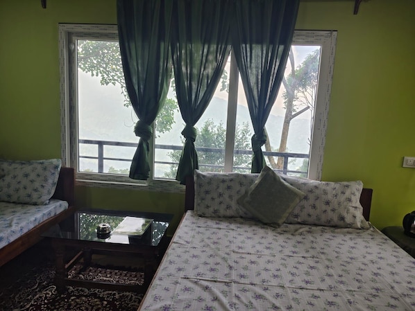 A room with a bed, a sofa, a small table, and a window with curtains.