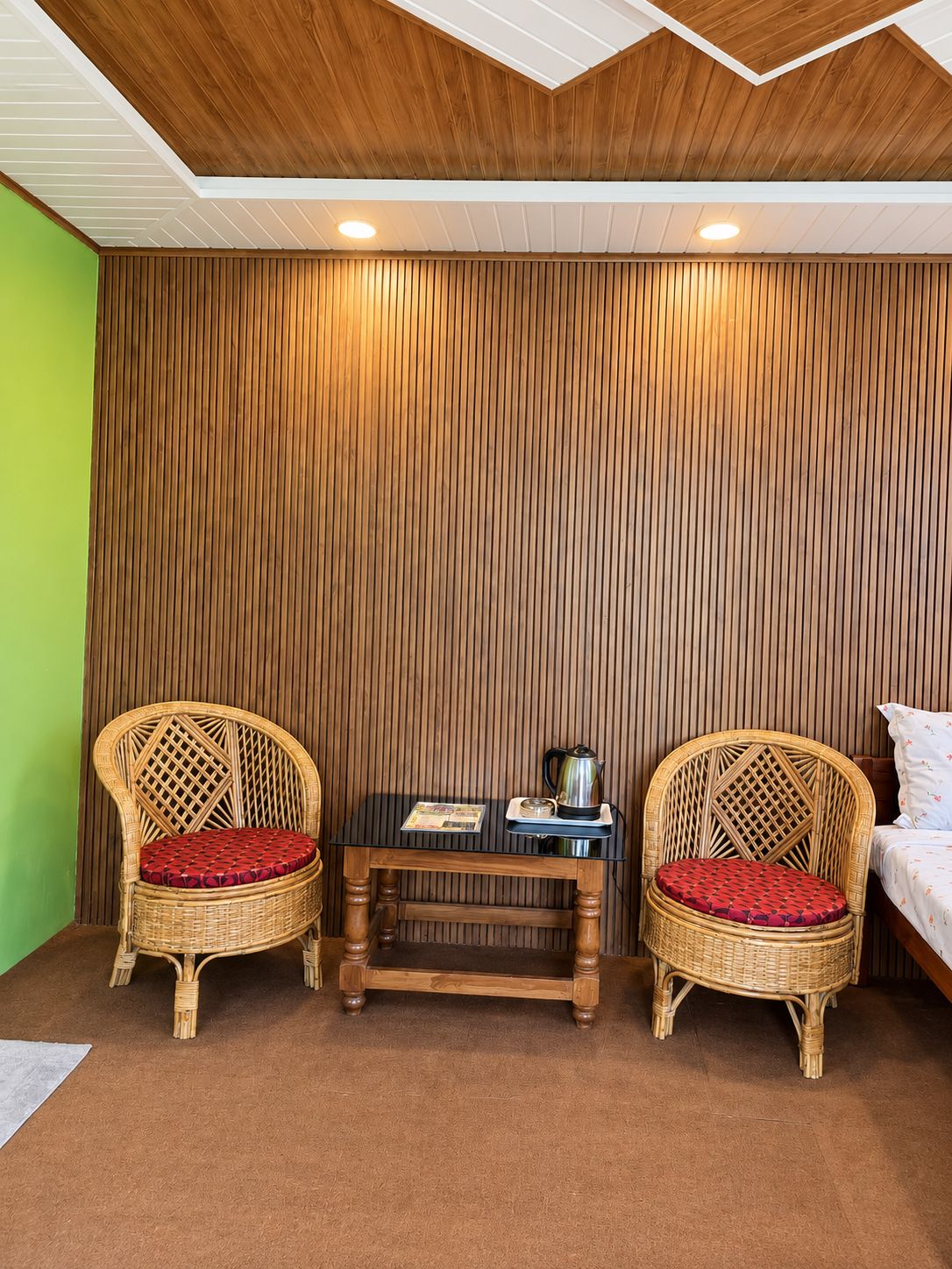 Una habitación con dos sillones de mimbre, una mesita de madera y una cama.