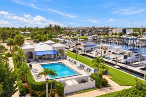 A marina with boats docked, a swimming pool with lounge chairs, and a building with a blue awning. - Imb308 2 Bedroom Home (Punta Gorda)