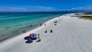 A wide sandy beach with clear turquoise water, a few people, and a colorful umbrella. - Downtown Sarasota House. Enjoy the Cultural side of area and 15 mins to Beach (Sarasota)