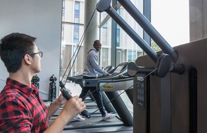Ein Fitnessraum mit Laufbändern und einer Person, die eines benutzt.