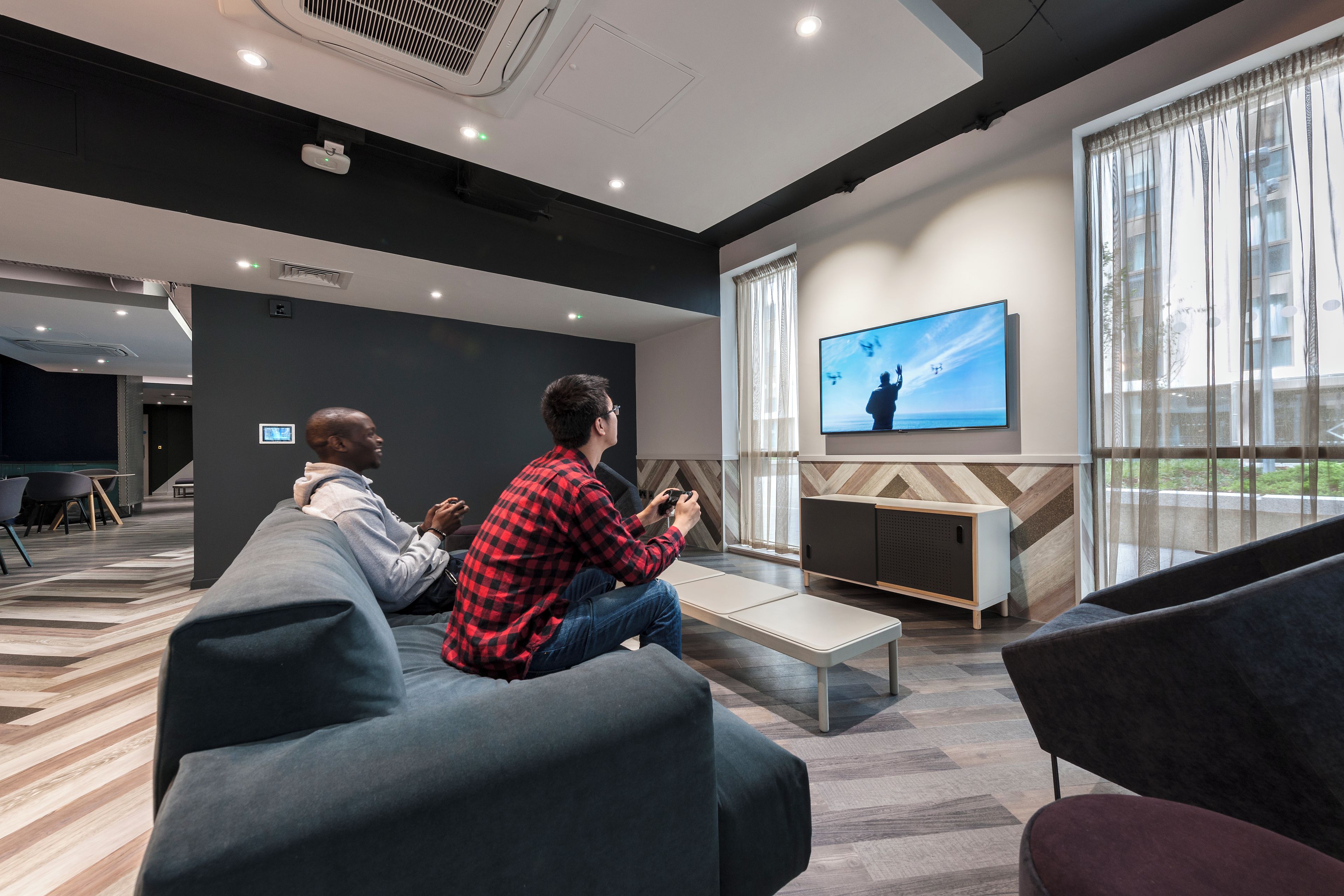 A modern lounge area with seating, a television, and a large window.