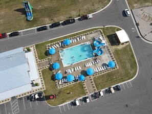 An aerial view of a parking lot with a swimming pool, lounge chairs, and a water slide. - Spacious 19' Wide × 57' Long RV Site Full Hookups & Resort Amenities. London, KY (London)