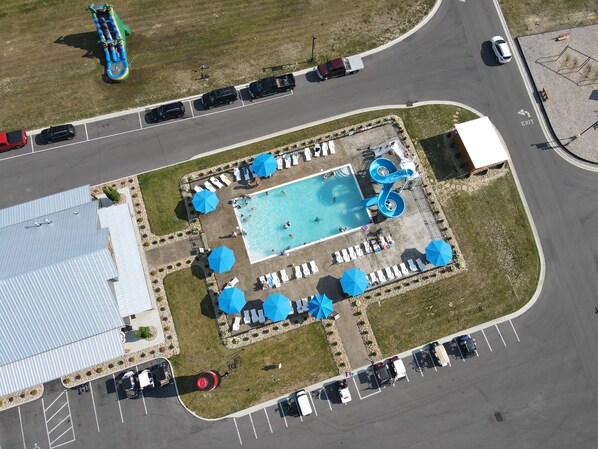 An aerial view of a parking lot with a swimming pool, lounge chairs, and a water slide.