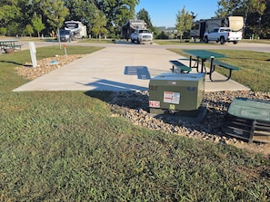 A campground with picnic tables, RVs, and a utility box.