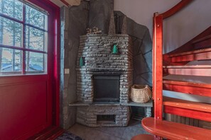 Ein Kamin aus Stein mit Schornstein, eine rote Tür und eine Holztreppe.