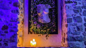 Un muro in pietra con una nicchia rettangolare che ospita una scultura a busto bianco, circondata da edera.