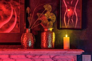 A fireplace mantel with two decorative vases and a lit candle.