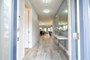 A hallway with a modern design, featuring a light-colored tiled floor, a glass partition on the right, and a door on the left. - Amazing 9 bedrooms and private pool with spa (Kissimmee)