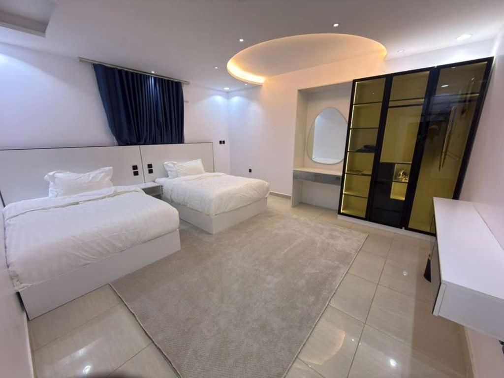 Une chambre d’hôtel moderne avec deux lits, un grand miroir et un placard à portes coulissantes.