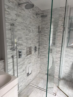 Un bagno moderno con box doccia in vetro, pavimento in marmo e vaso WC a incasso.
