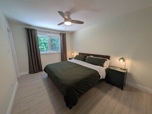 Una camera da letto con un letto, una ventola a soffitto, una finestra con tende e lampade sui comodini.