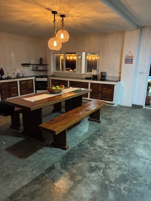 Een keuken met een centraal eiland, houten kastjes en een hanglamp.