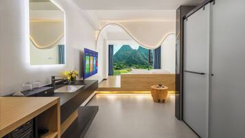 A modern bathroom with a large mirror, a sink, and a vanity. There is a view of a mountainous landscape through the window.