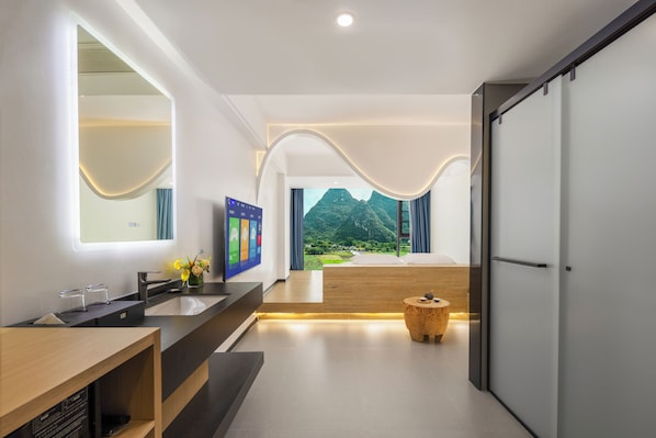 A modern bathroom with a large mirror, a sink, and a vanity. There is a view of a mountainous landscape through the window.