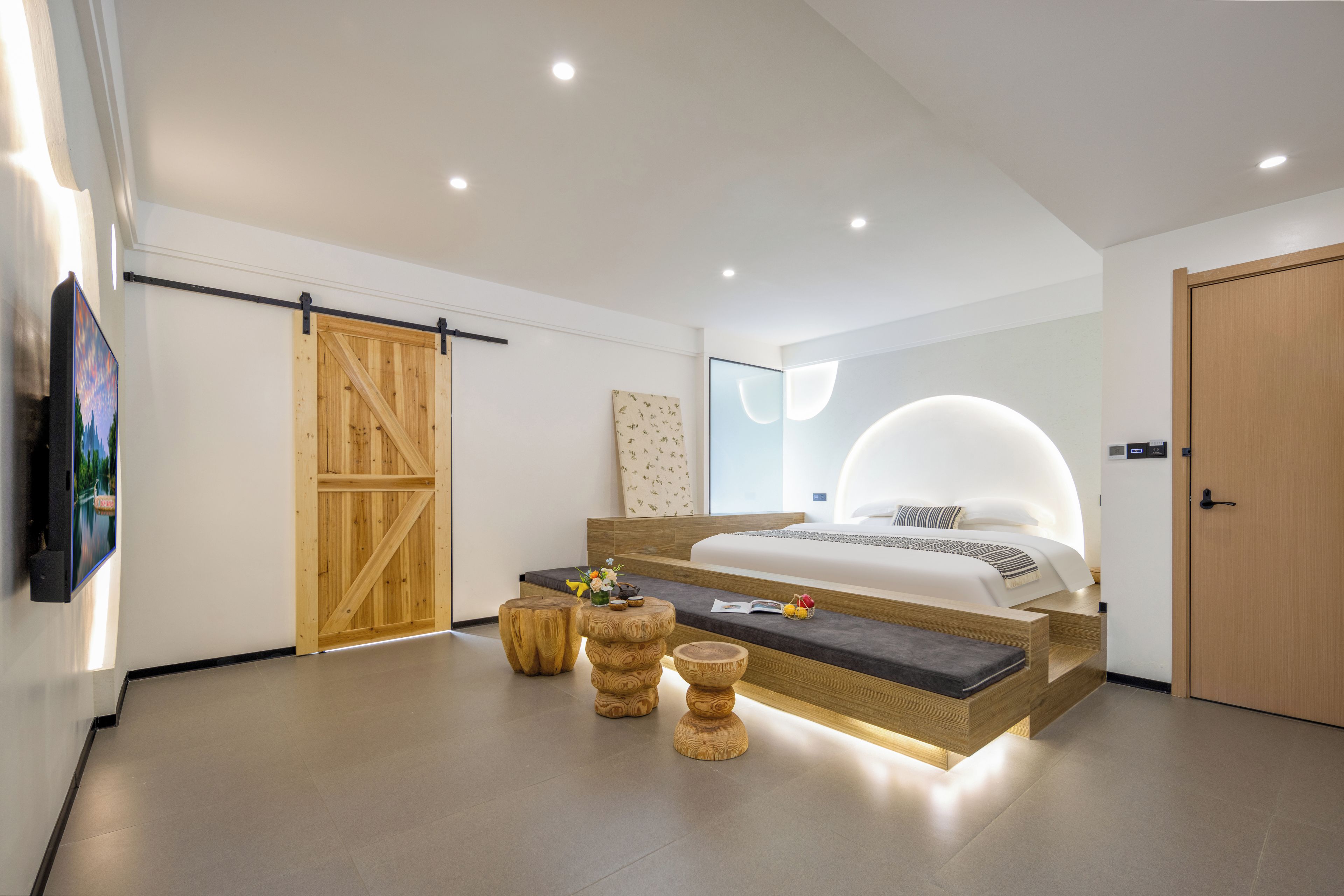 A modern bedroom with a large bed, wooden furniture, and a sliding door.