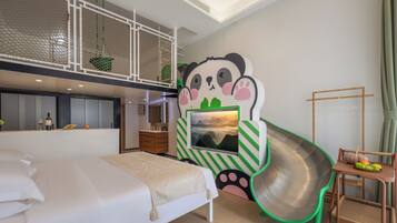 A bedroom with a bed, a desk, a chair, a panda mural, a hanging plant, and a window.