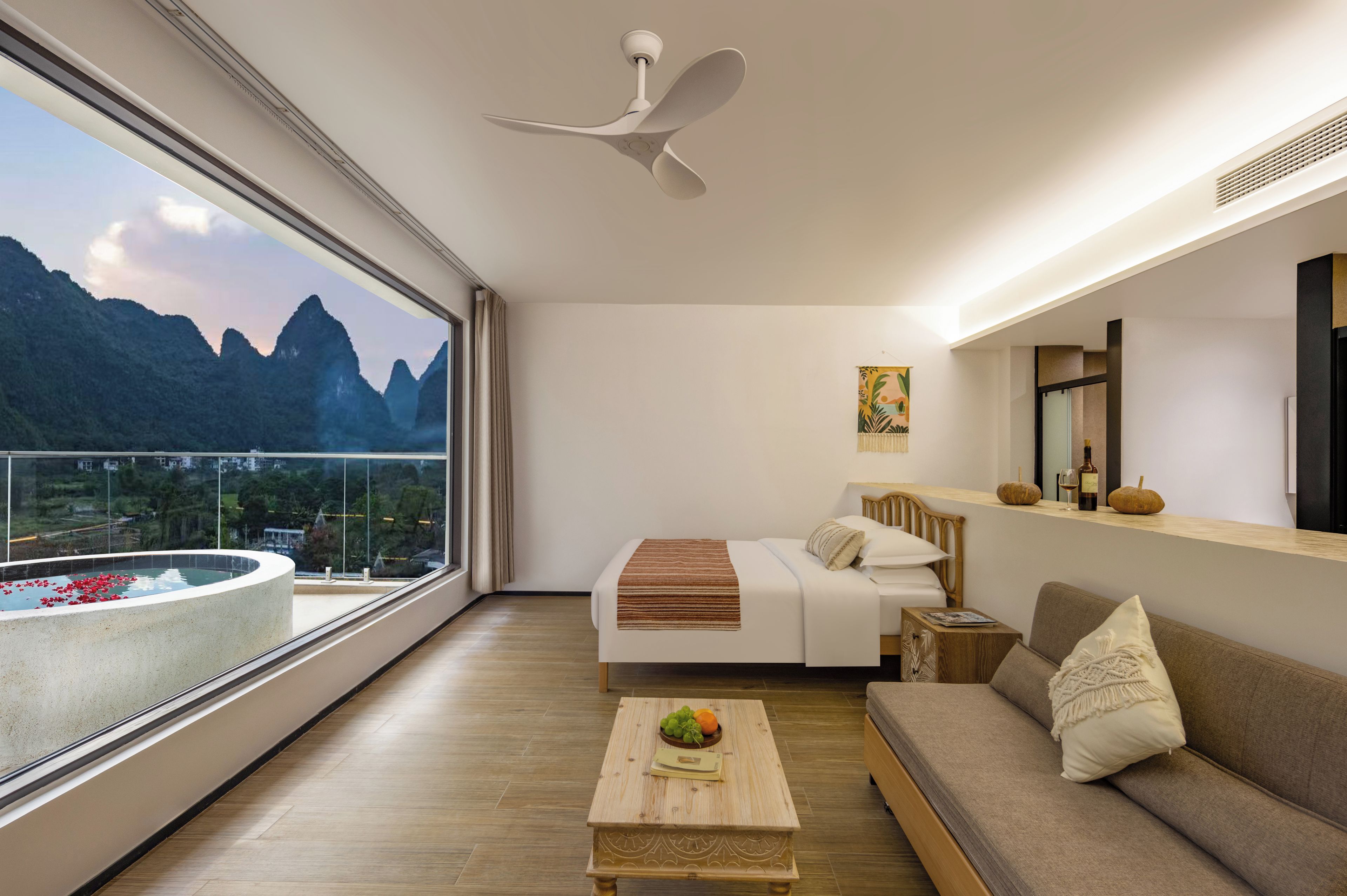 Een moderne hotelkamer met een balkon, een bed, een slaapbank, een salontafel en uitzicht op bergen.