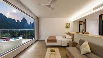 Een moderne hotelkamer met een balkon, een bed, een slaapbank, een salontafel en uitzicht op bergen.