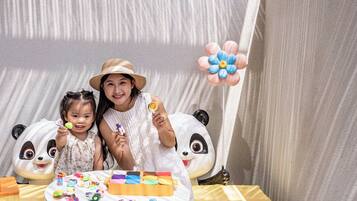 A room with a large window, a table with toys, and a panda decoration.