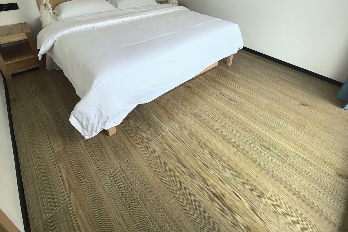 A room with a bed, a nightstand, and a wooden floor.