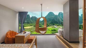 A modern room with a hanging chair, a bed, a table with a basket, and a view of a mountainous landscape.