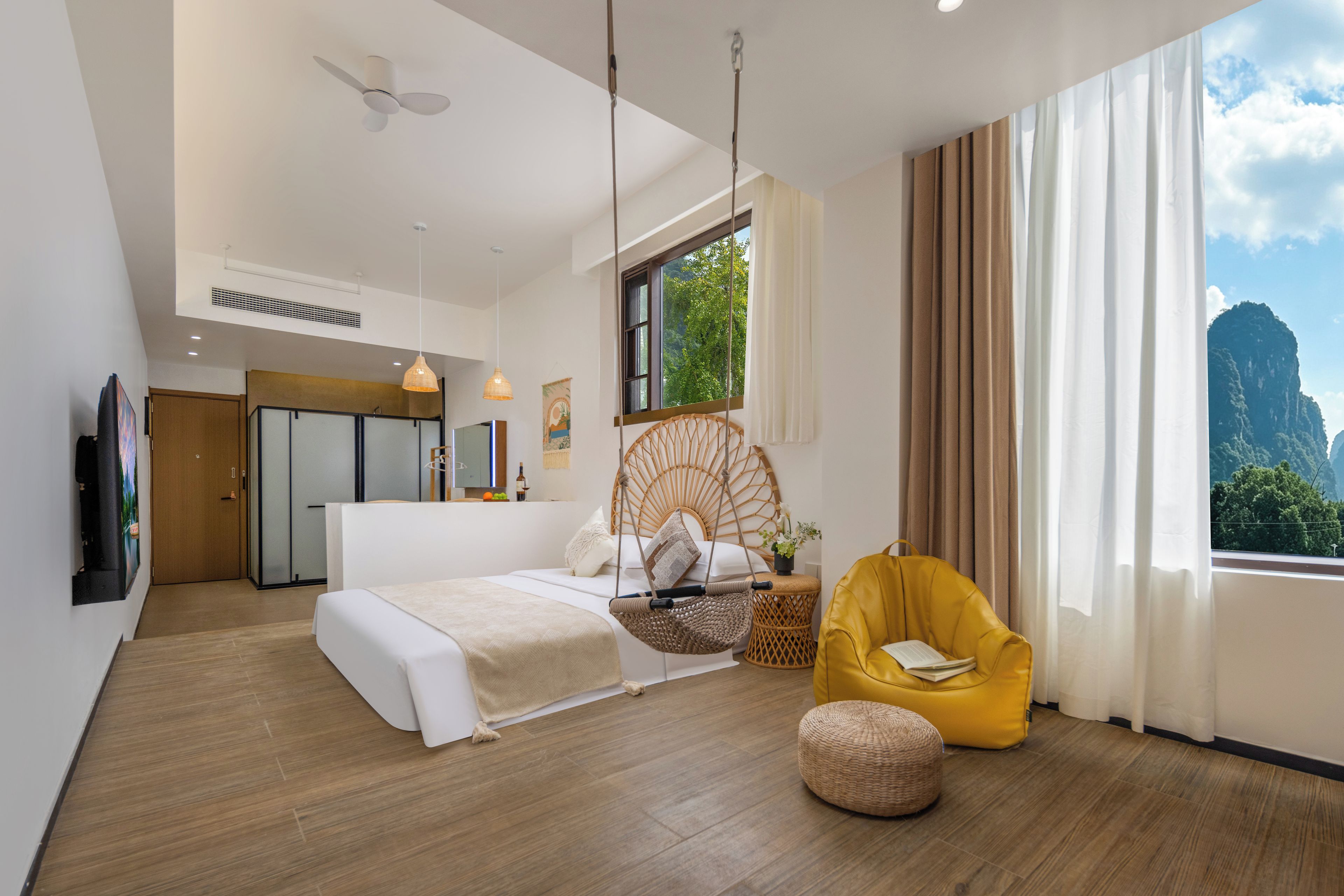 Een moderne hotelkamer met een bed, een hangstoel, een klein bijzettafeltje en een groot raam met uitzicht op de bergen.