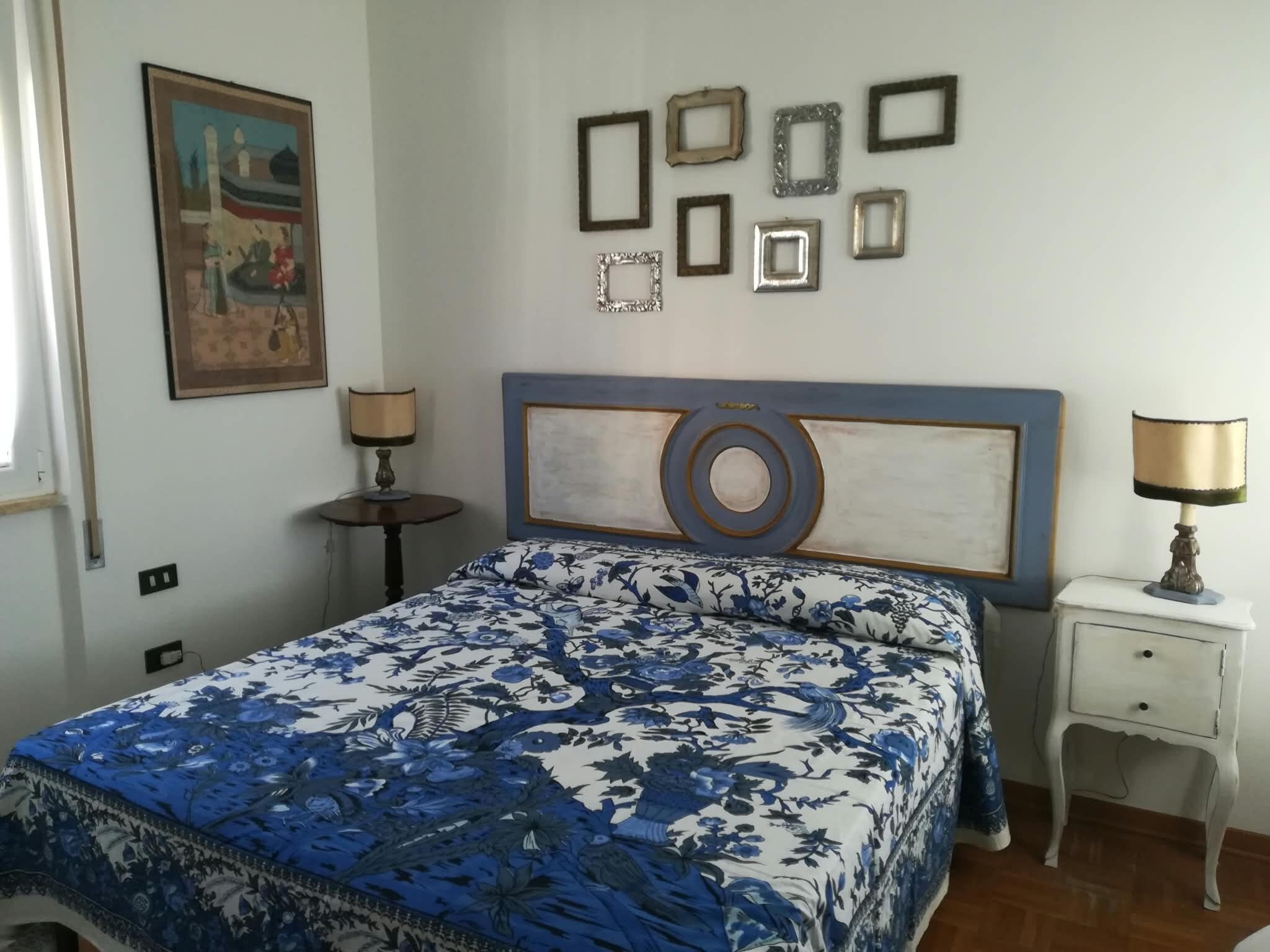 Una camera da letto con un letto, due comodini, una lampada a parete e un quadro incorniciato.