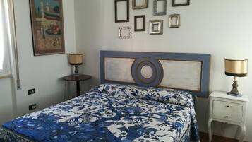 Una camera da letto con un letto, due comodini, una lampada a parete e un quadro incorniciato.