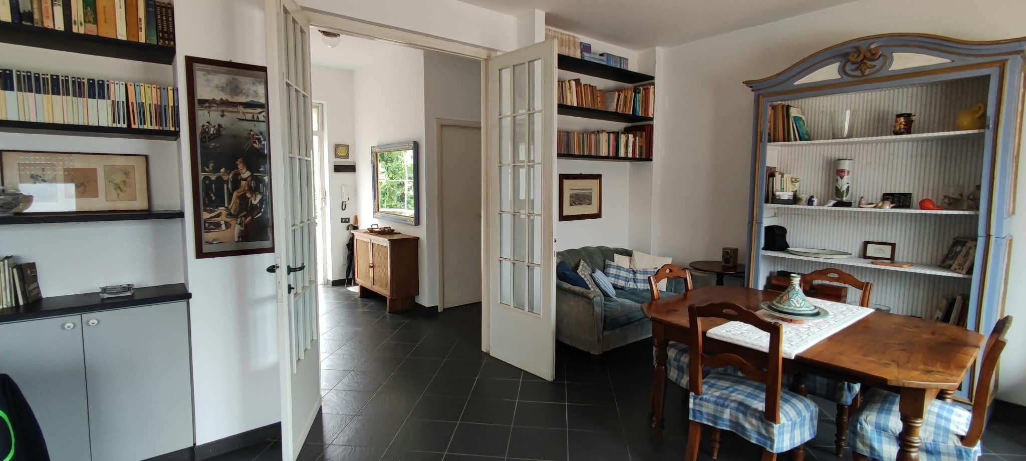 Una stanza con un tavolo da pranzo, sedie, una libreria e una porta che dà su un'altra stanza.