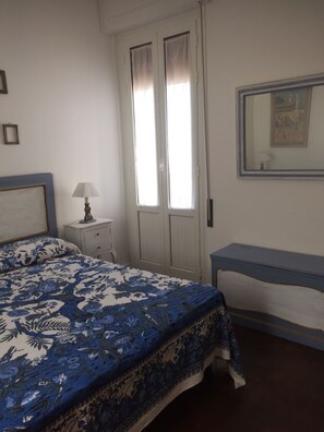 Una camera da letto con un letto, un comodino, una lampada e una scrivania.
