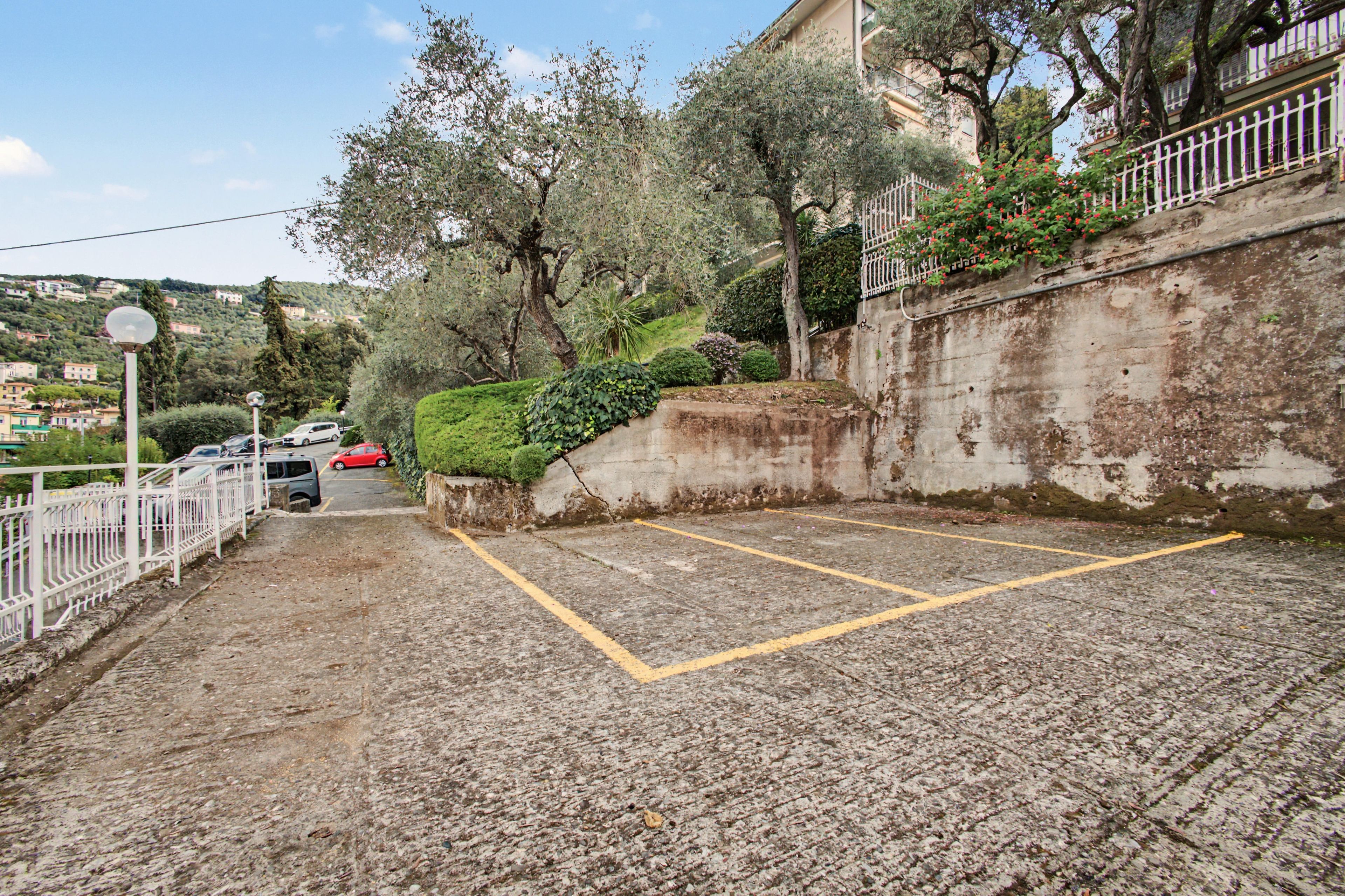 Un'area di parcheggio con un muro in cemento e una recinzione bianca.
