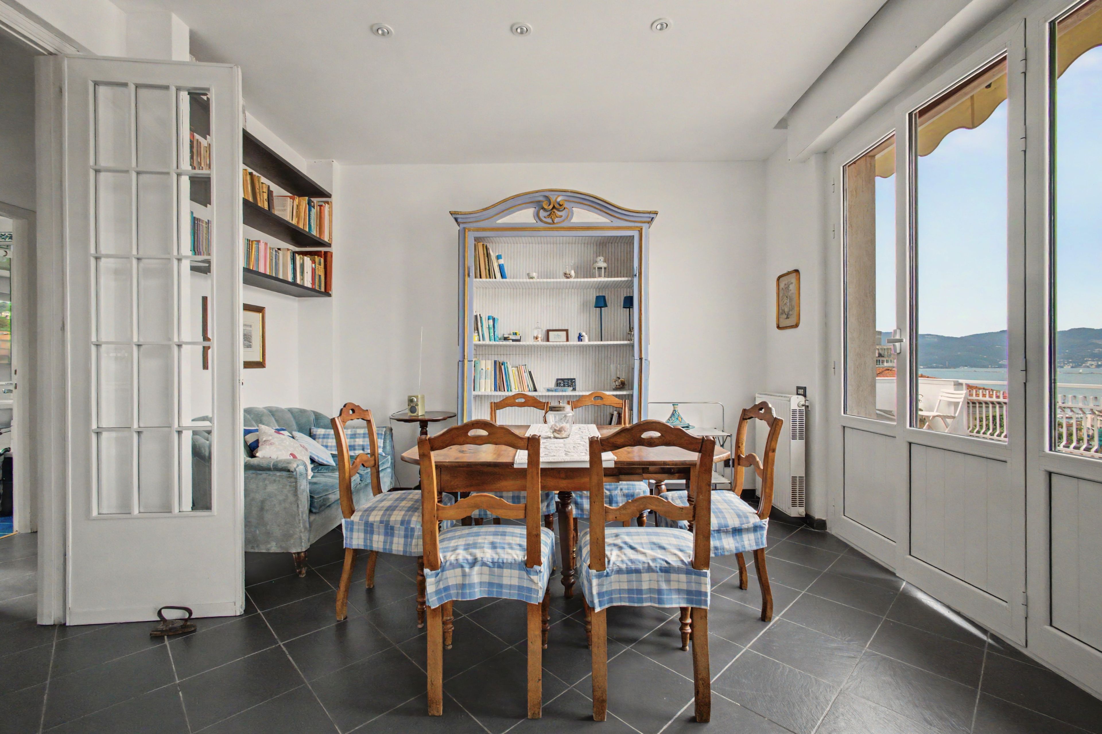 A dining area with a table set for four, surrounded by wooden chairs with checkered seat covers.