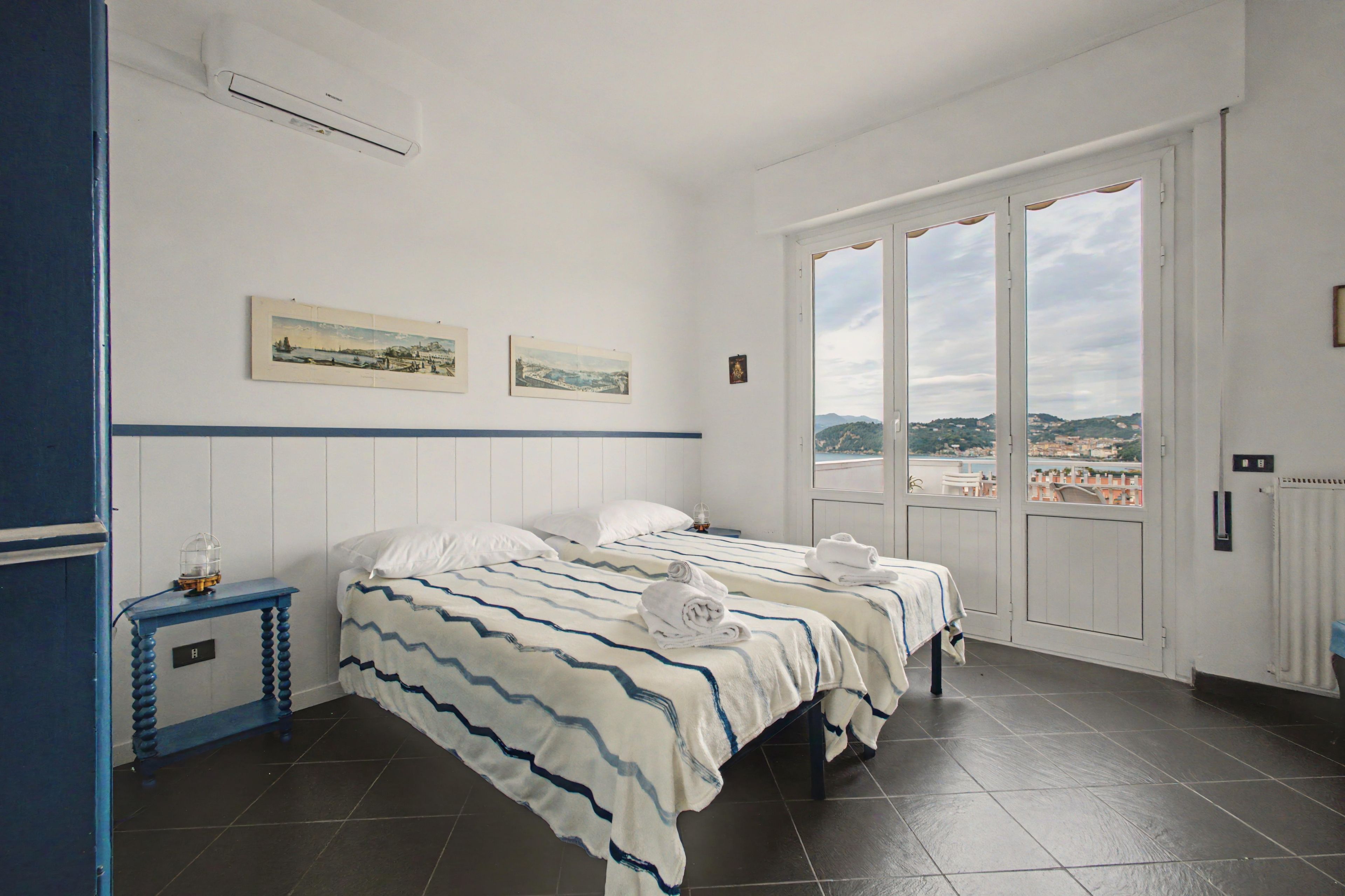Quarto de hotel com duas camas, vista para a cidade e janela com cortinas.