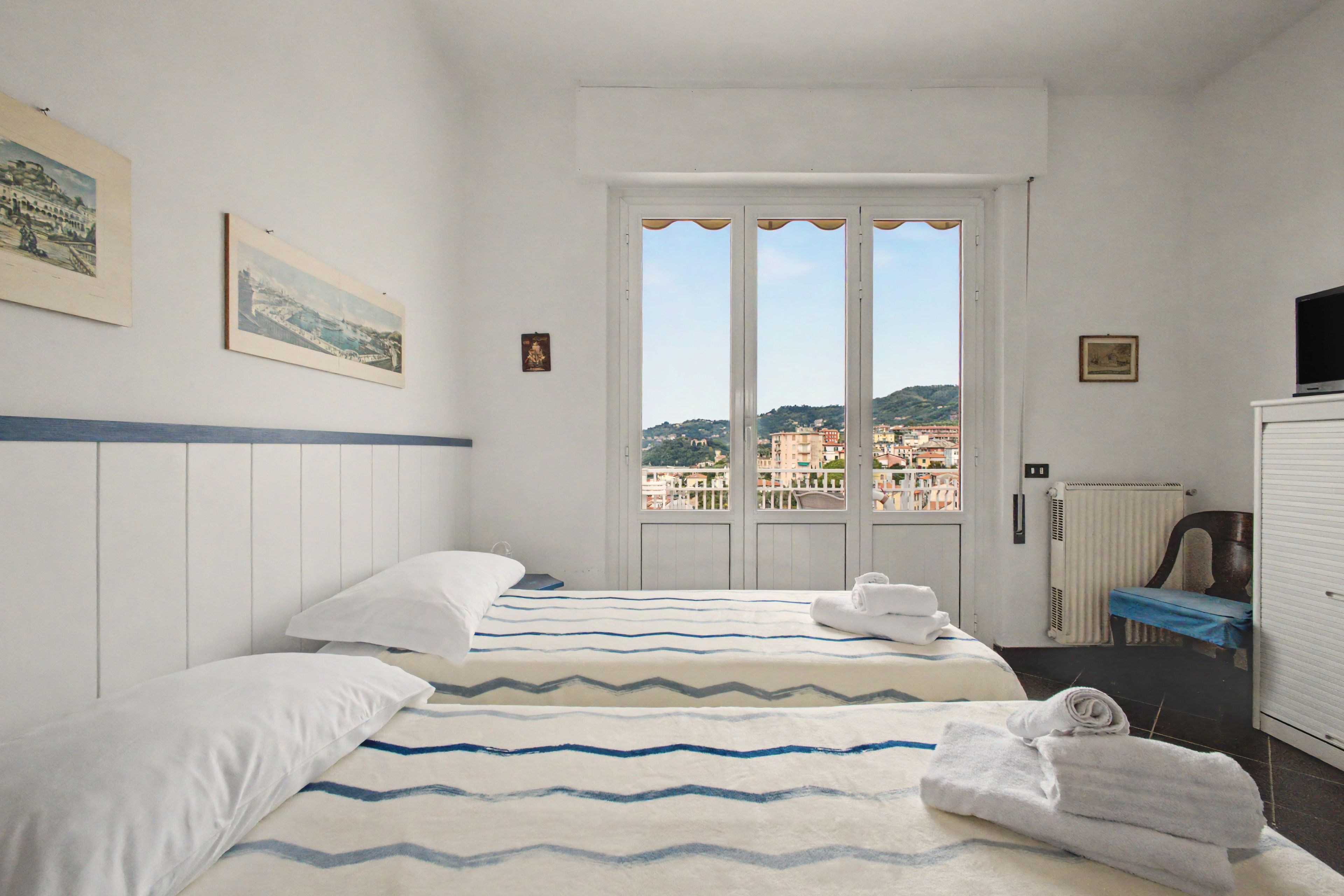 Camera d'albergo con due letti, vista sulla città e televisione.